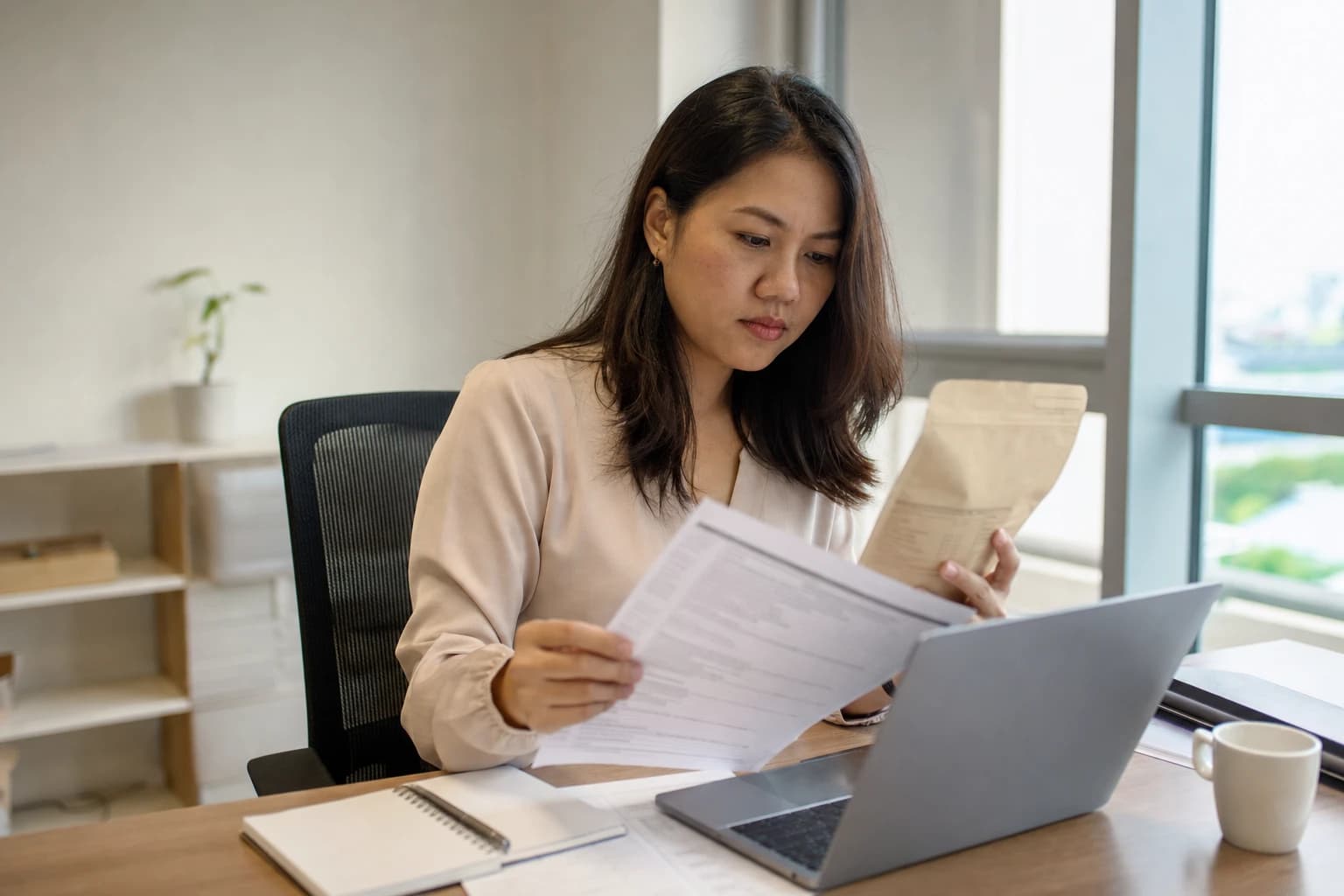 A regulatory affairs specialist checking a prepacked food product's ingredient list against a flavour supplier's specification sheet at a desk in Singapore